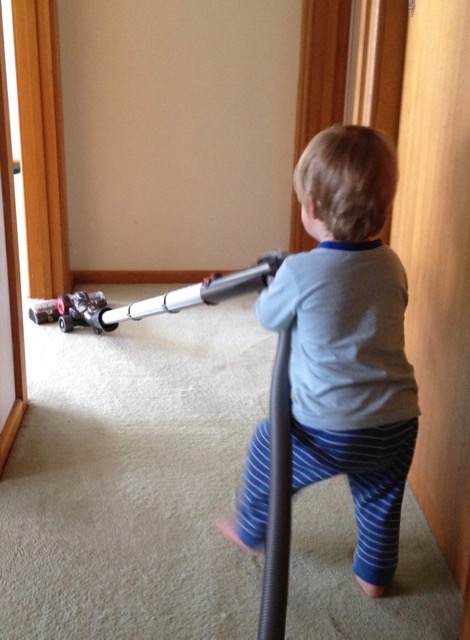 Small child vacuuming carpet.