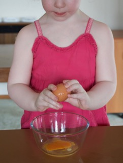 child cracking eggs into a bowl