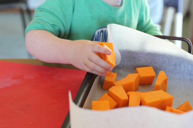 child placing pumpkin on tray for baking